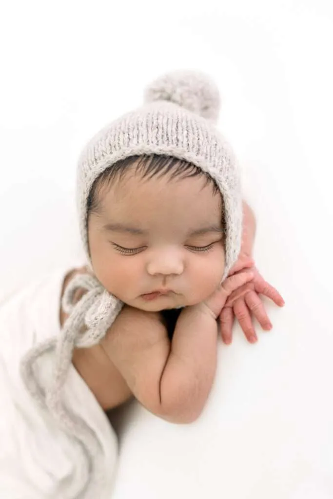 newborn boy sleeping in a bonnet