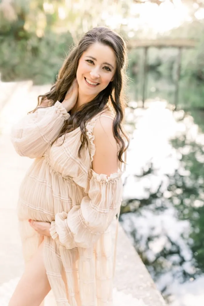 woman posing for maternity photo along the river