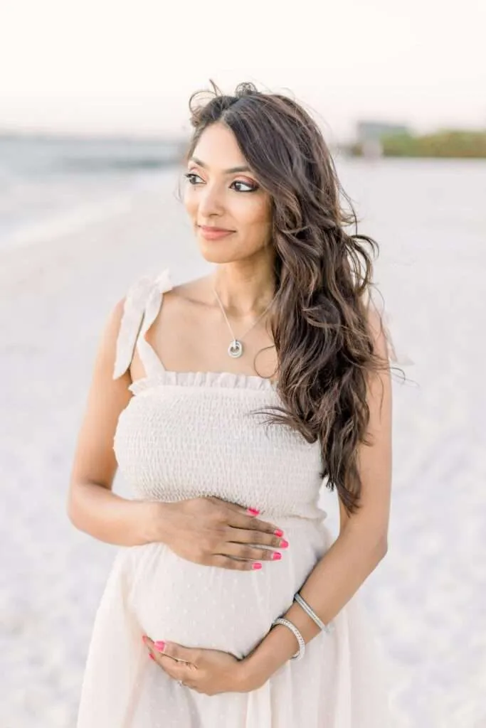 woman on beach holding baby bump