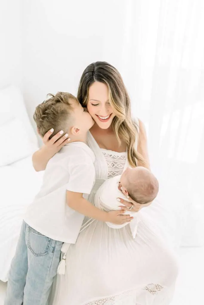 mom holding newborn and son