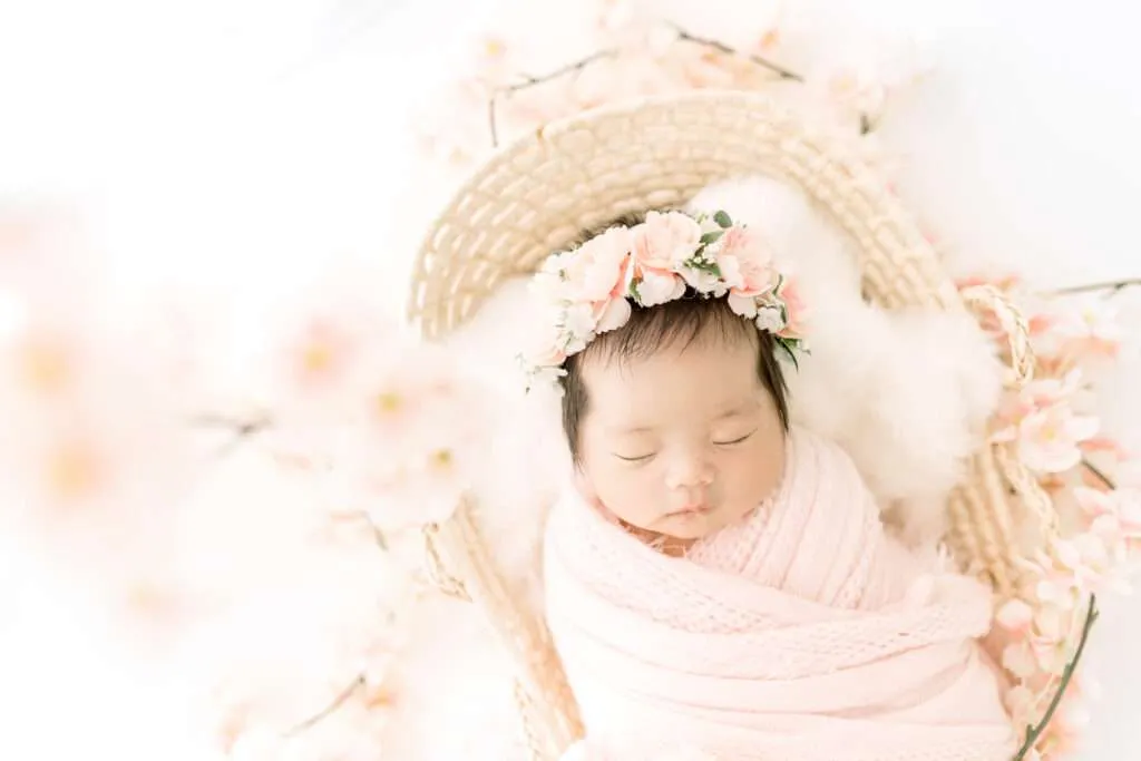 newborn girl in a basket with cherry blossoms