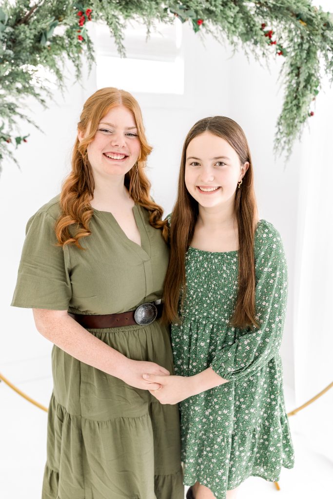 sisters in green dresses for christmas photo mini session