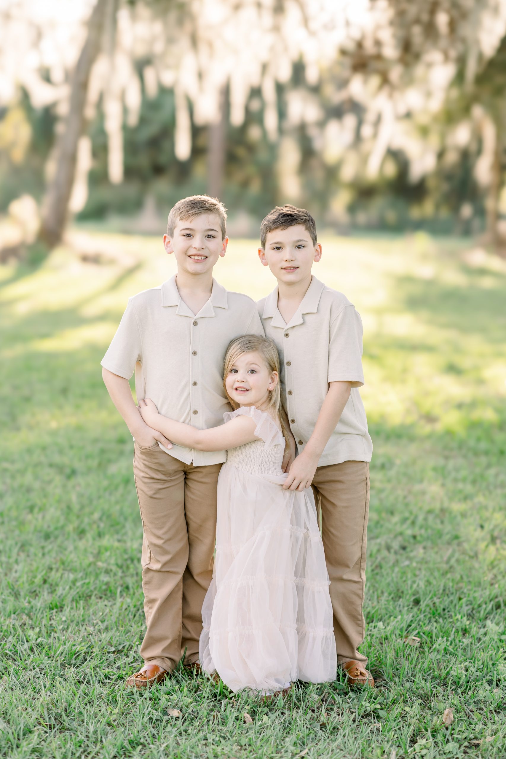siblings hugging under oak tree for family session