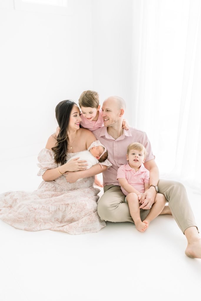Family of five wearing coordinated pink and khaki outfits for a timeless newborn photography session in Tampa, Florida.